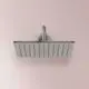 Duschkopf von Ideal Standard, rechteckig mit gleichmäßig verteilten Düsen, montiert an einer Wand in einem Raum mit rosa Hintergrund.